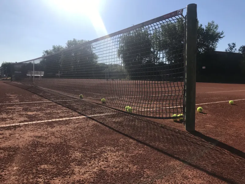 Tennisnetz mit Bällen auf dem Sandplatz in der Sonne