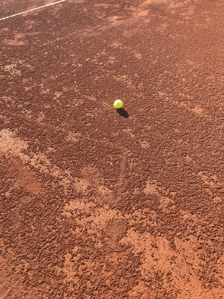 Tennisball auf rotem Sandplatz